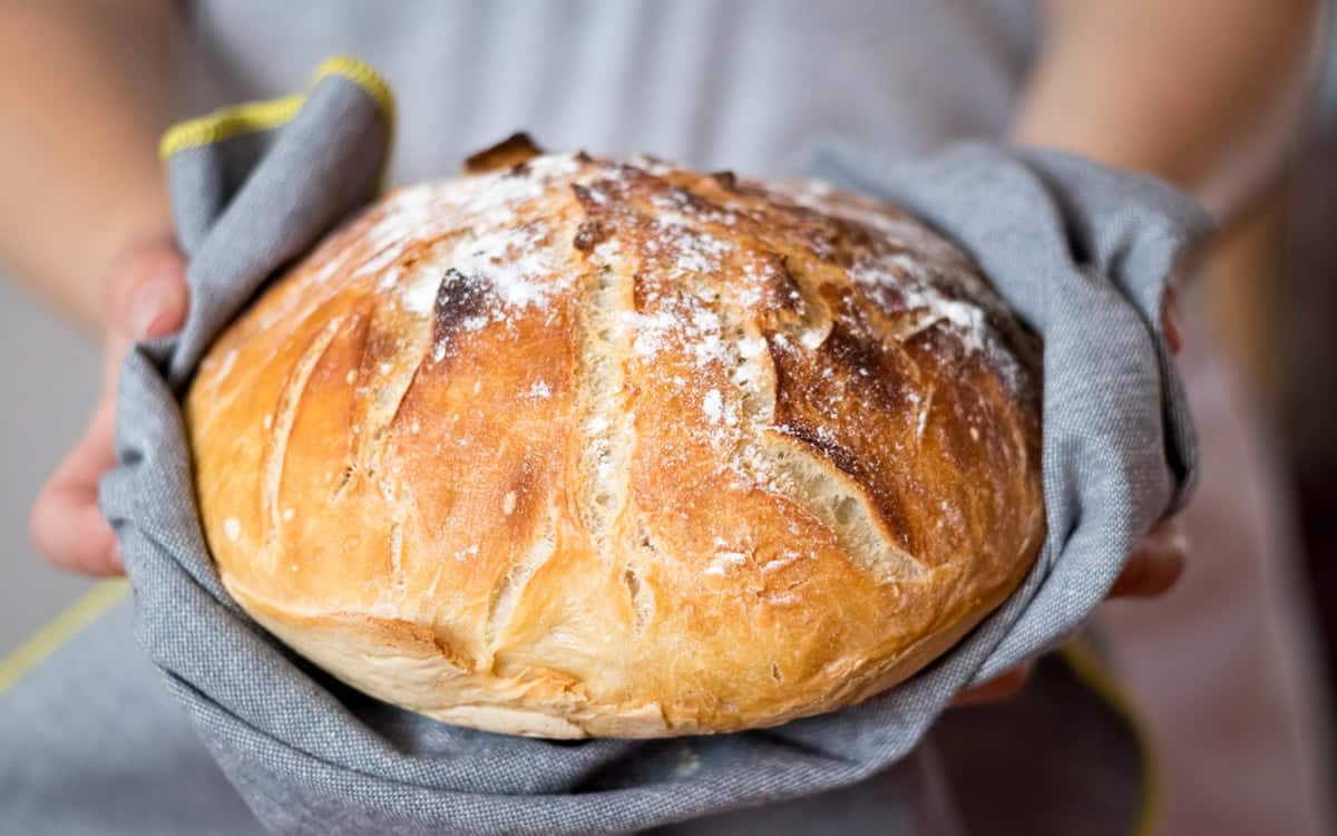 Dame som holder et nystekt eltefritt brød.