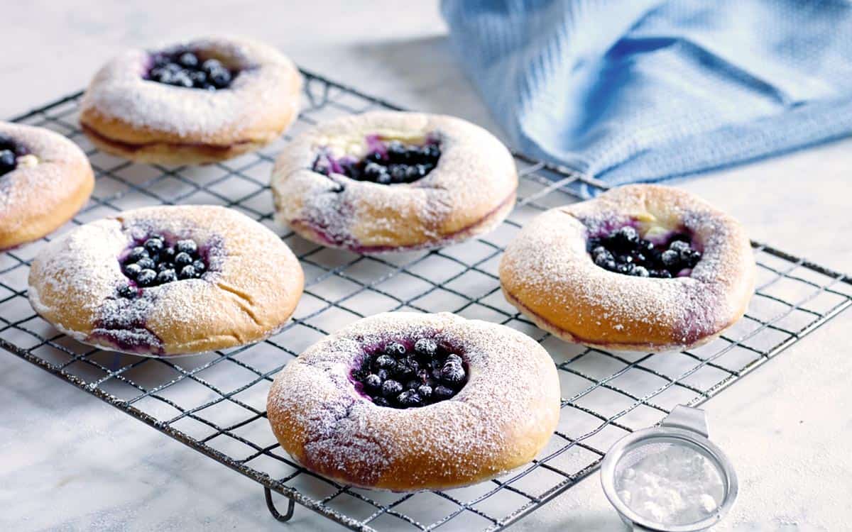 Skolebrød med blåbær og rømme på en bakerist.