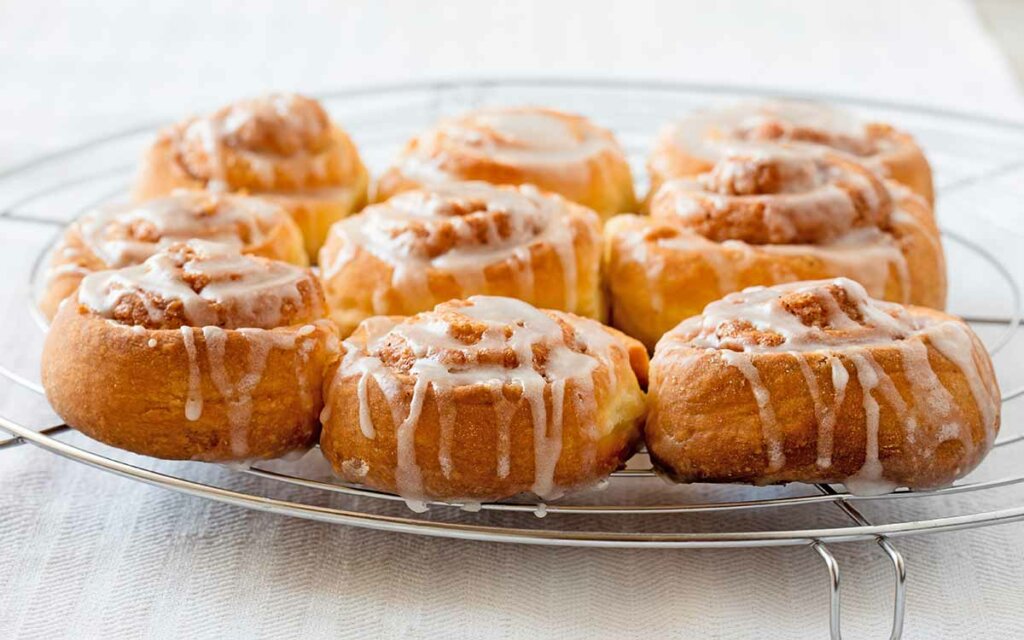 Nystekte glutenfrie kanelboller på en bakerist.