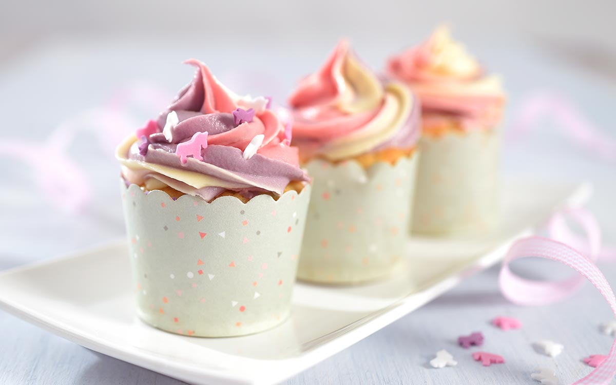Cupcake oppskrift viser cupcakes med farget smørkrem på toppen.