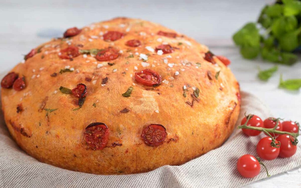 Tomatbrød som er formet rundt med cherrytomater på toppen.