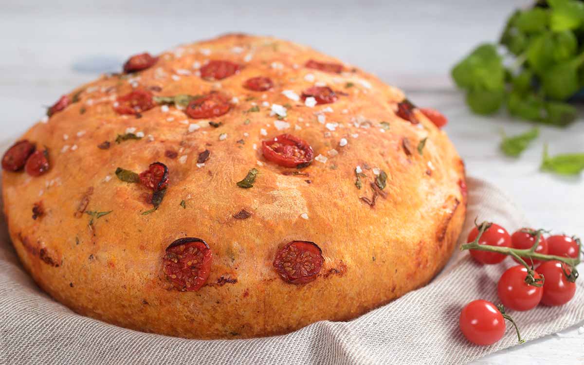 Tomatbrød som er formet rundt med cherrytomater på toppen.