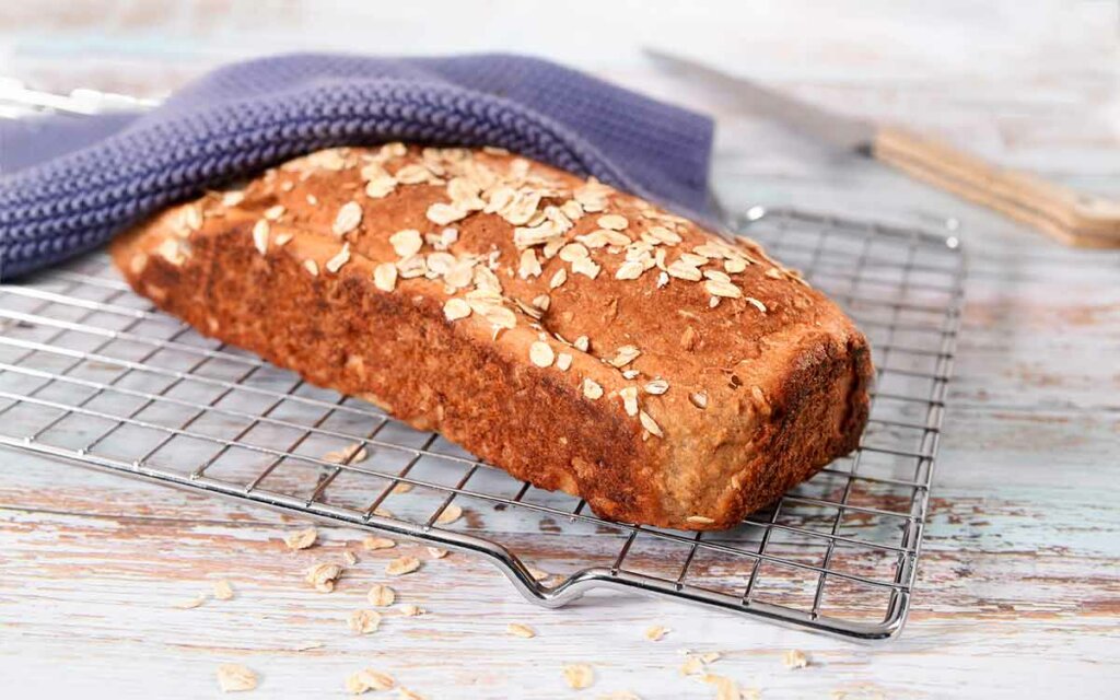 Hjemmebakt gluten og laktosefritt havrebrød på en bakerist.